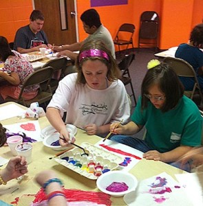 Participants sitting at tables working on art projects.